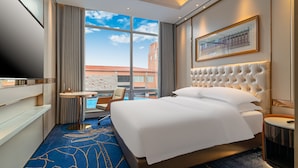 A hotel room with a large bed, a TV, a small round table, and a view of the cityscape. - Easeland Hotel  Guangzhou (Guangzhou)