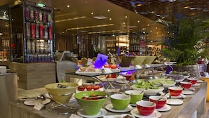 A buffet with various dishes and utensils, a glass display case, and a potted plant. - Easeland Hotel  Guangzhou (Guangzhou)