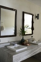 Une salle de bain avec deux lavabos, un miroir et une plante en pot.