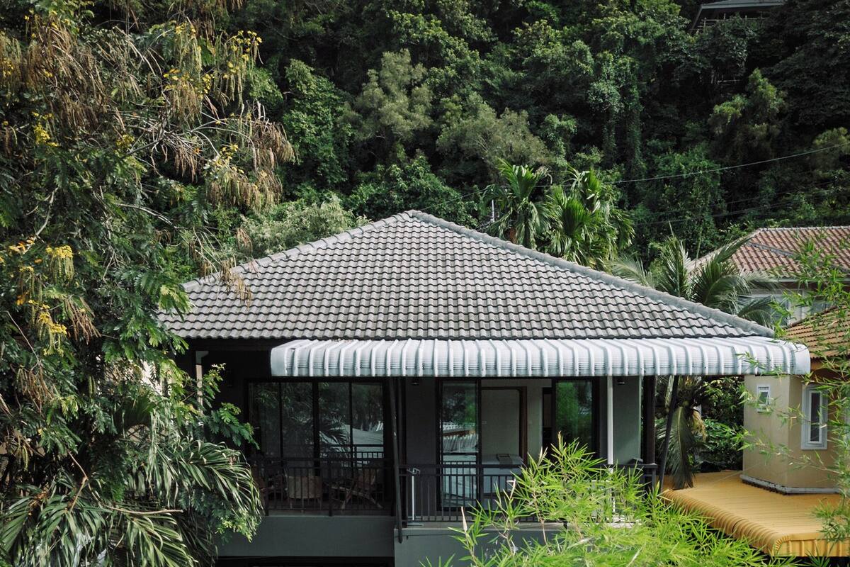 A modern house with a tiled roof, large windows, and a balcony.