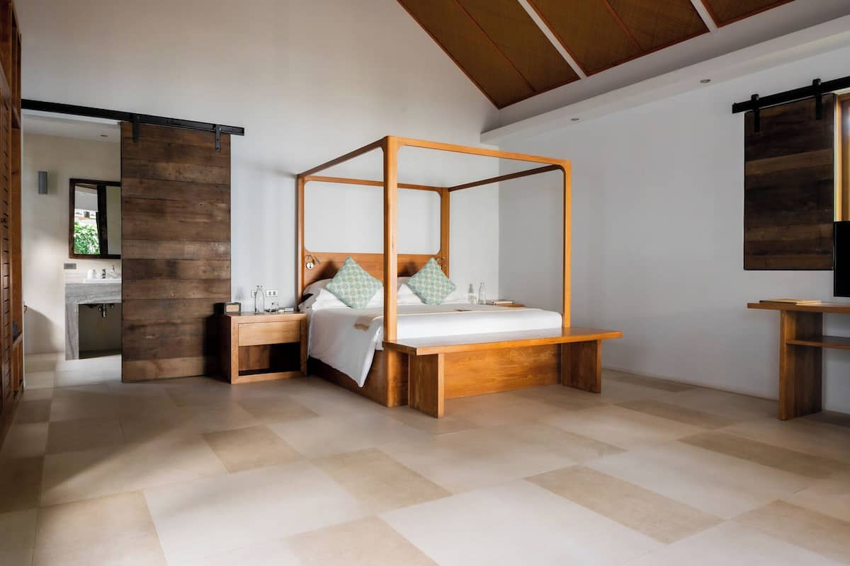 A modern bedroom with a four-poster bed, wooden nightstands, and a built-in desk.