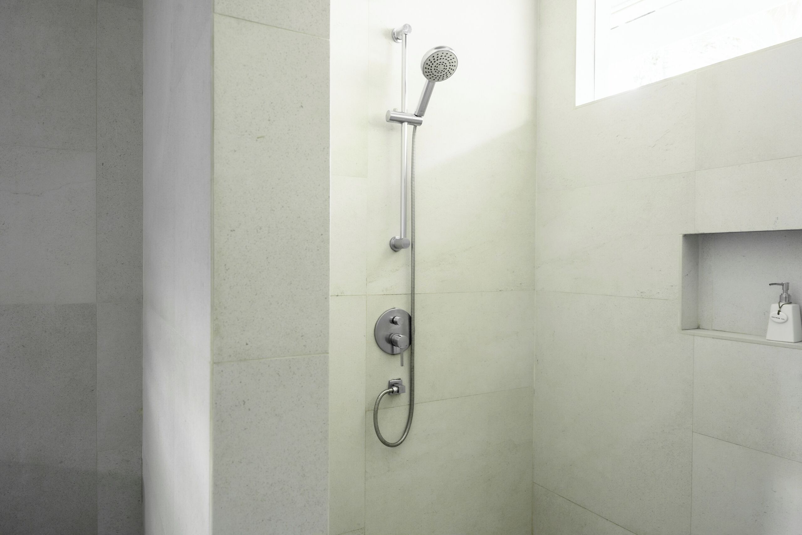 A modern shower with a handheld showerhead and a fixed wall-mounted head.