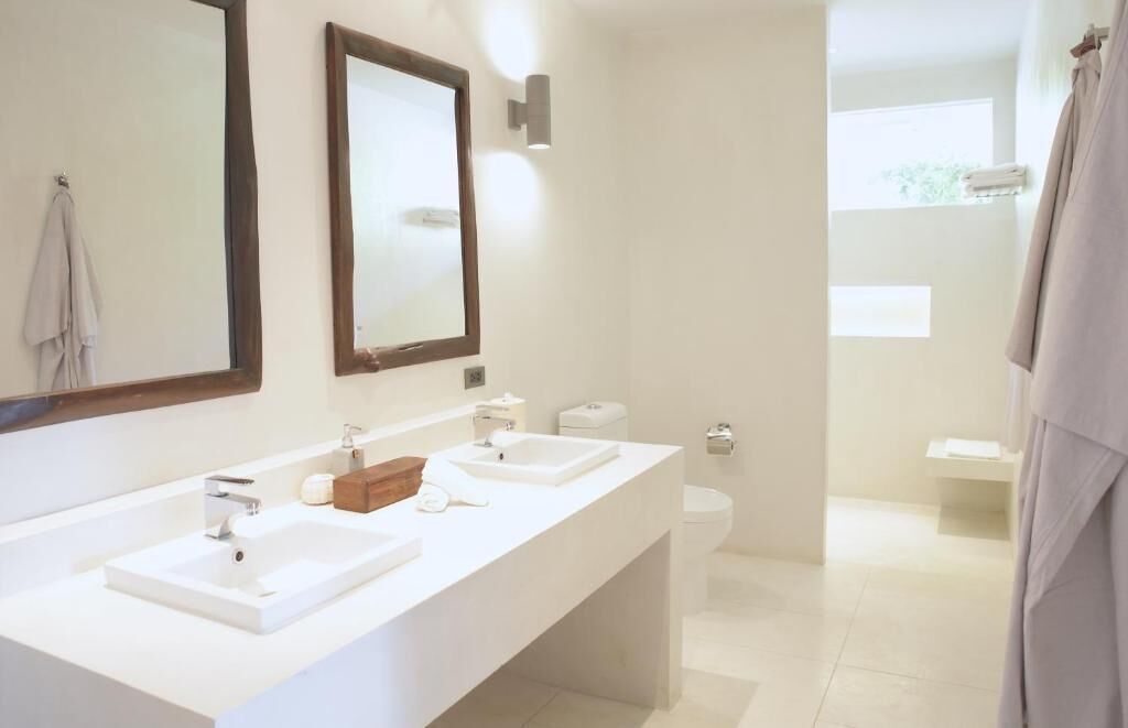 A modern bathroom with two sinks, a toilet, and a shower area.