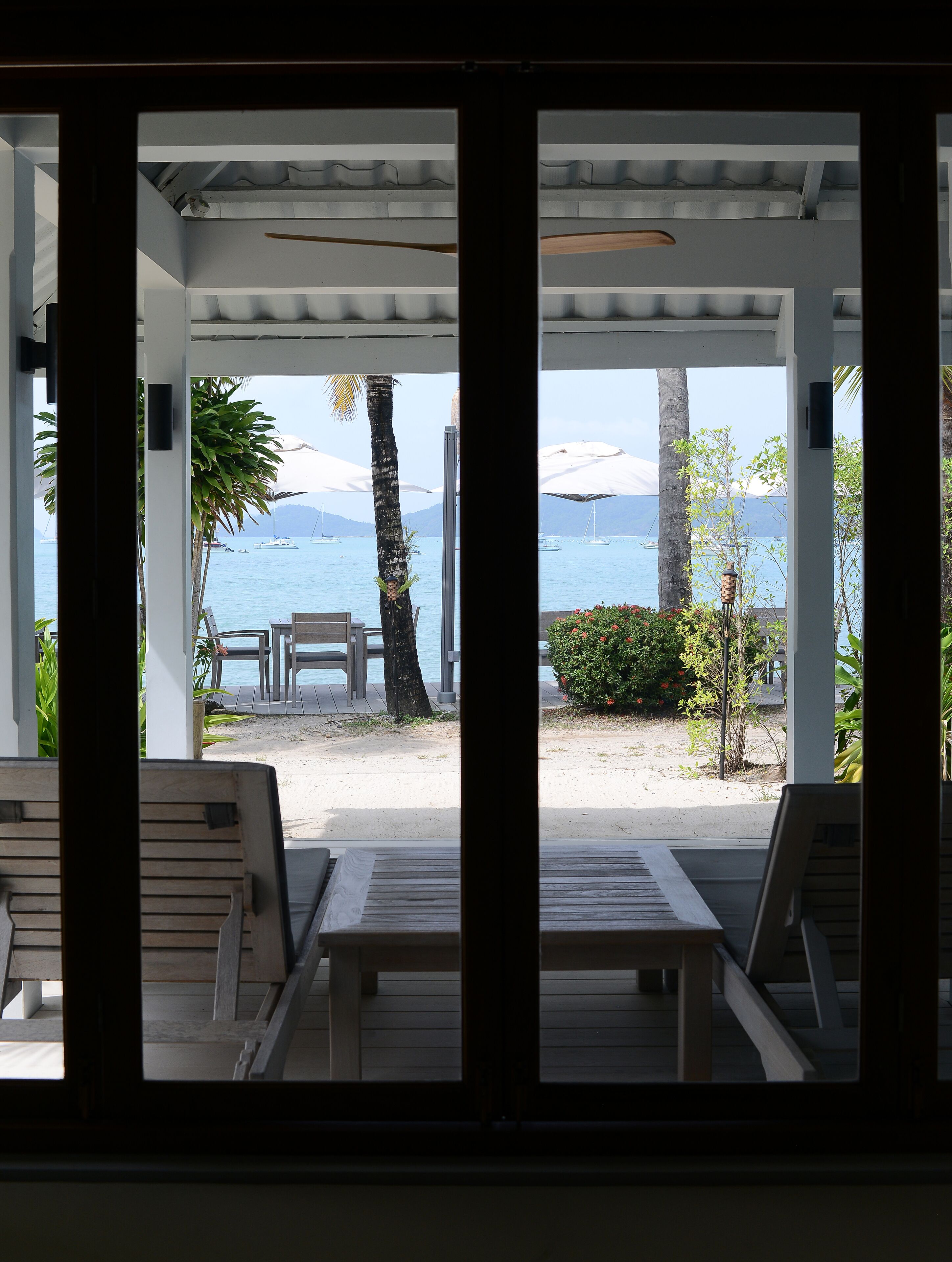 A covered outdoor seating area with a view of the beach and ocean.