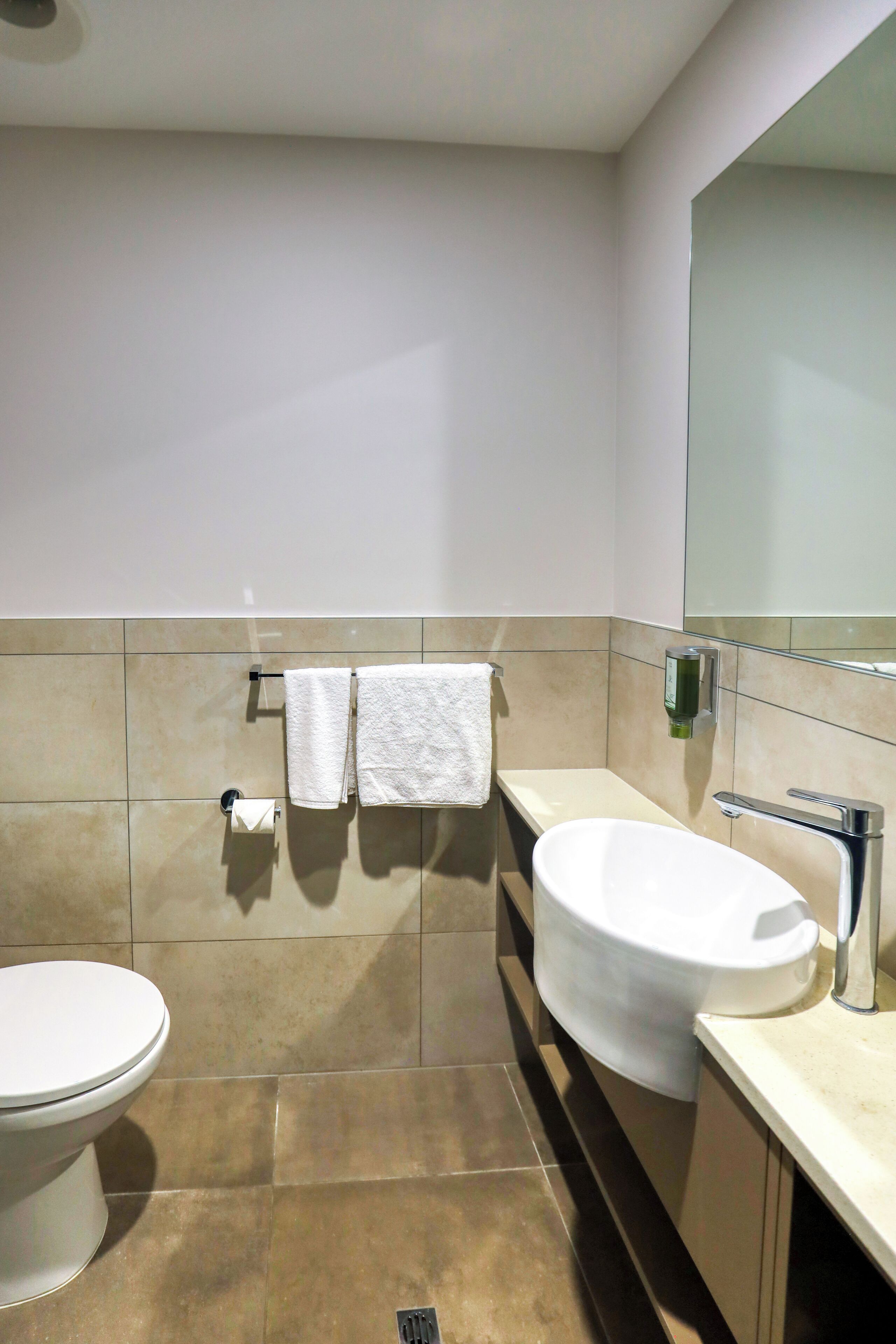 A modern bathroom with a toilet, sink, and mirror.
