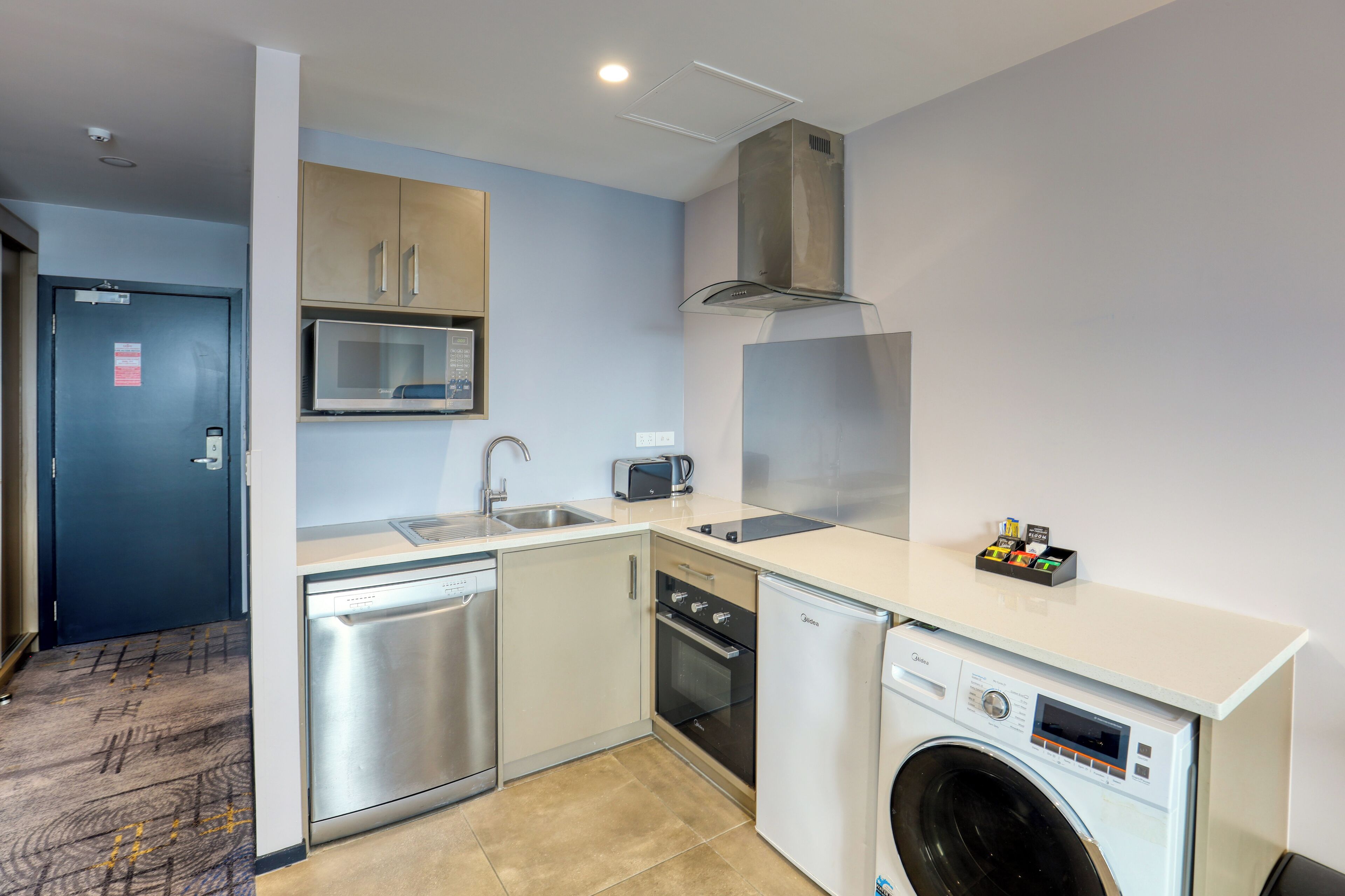 A compact kitchen with a dishwasher, oven, microwave, and a washing machine.