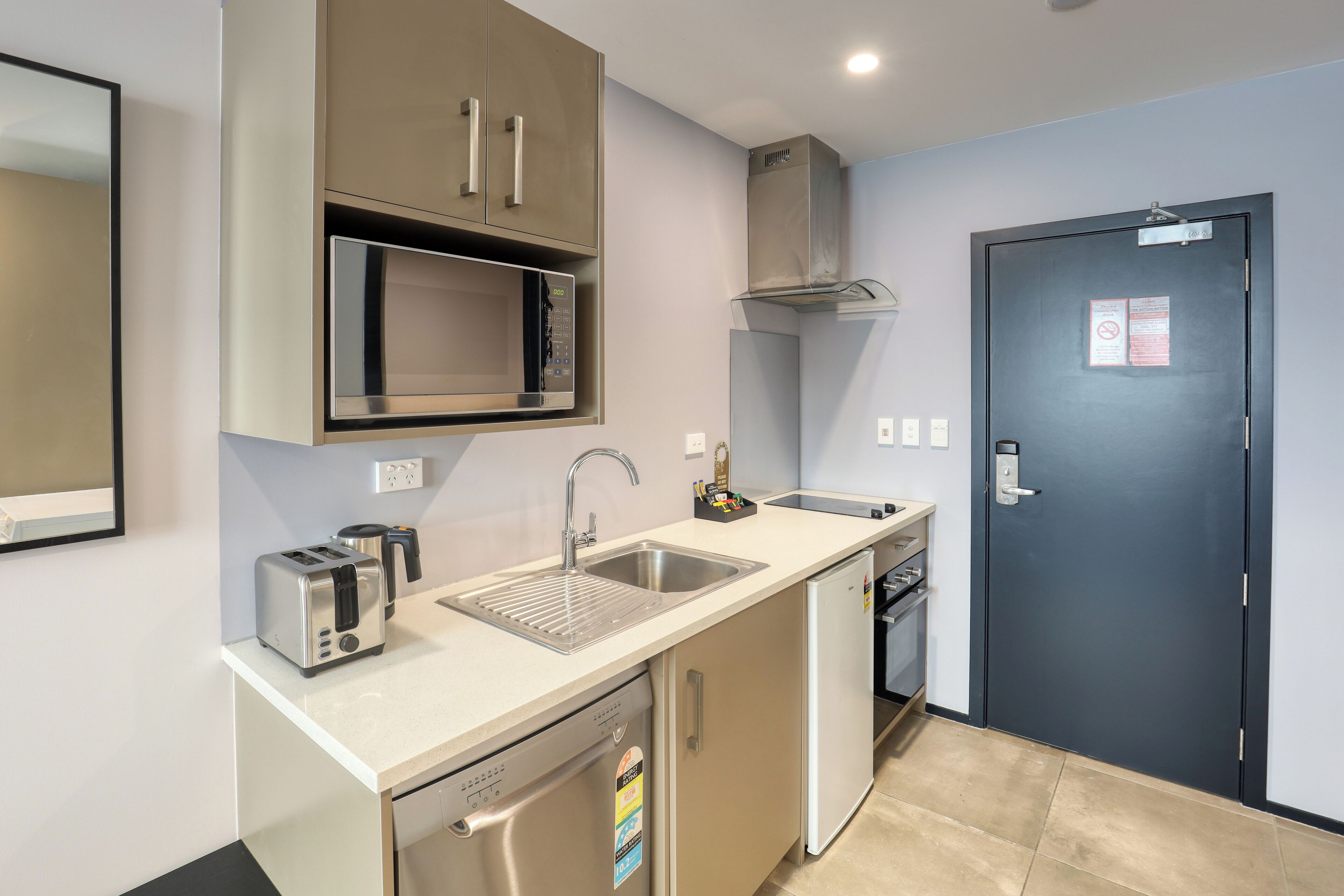 Una kitchenette compacta equipada con microondas, tostadora, pileta y lavavajillas.