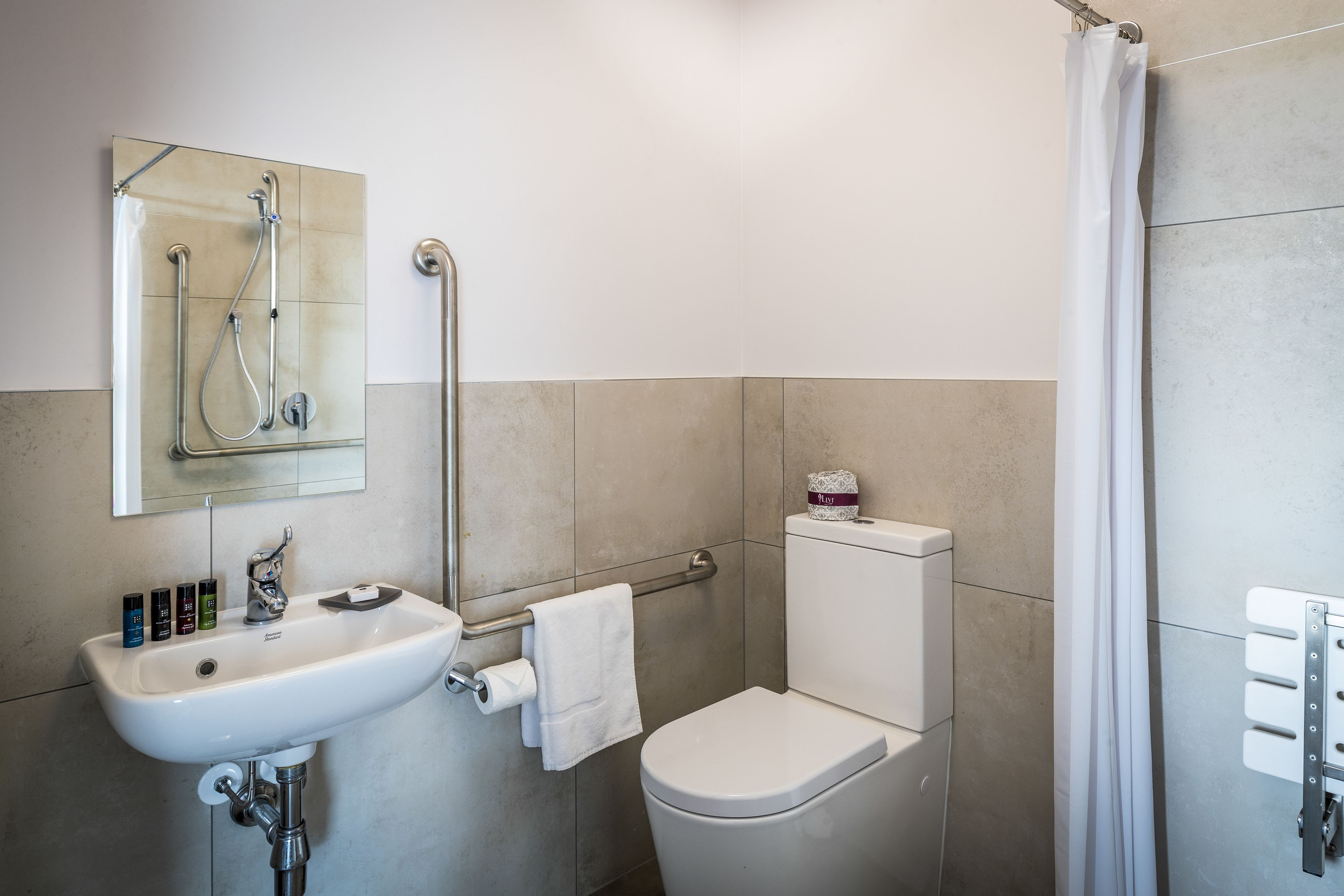 A bathroom with a white sink, mirror, toilet, and shower curtain.