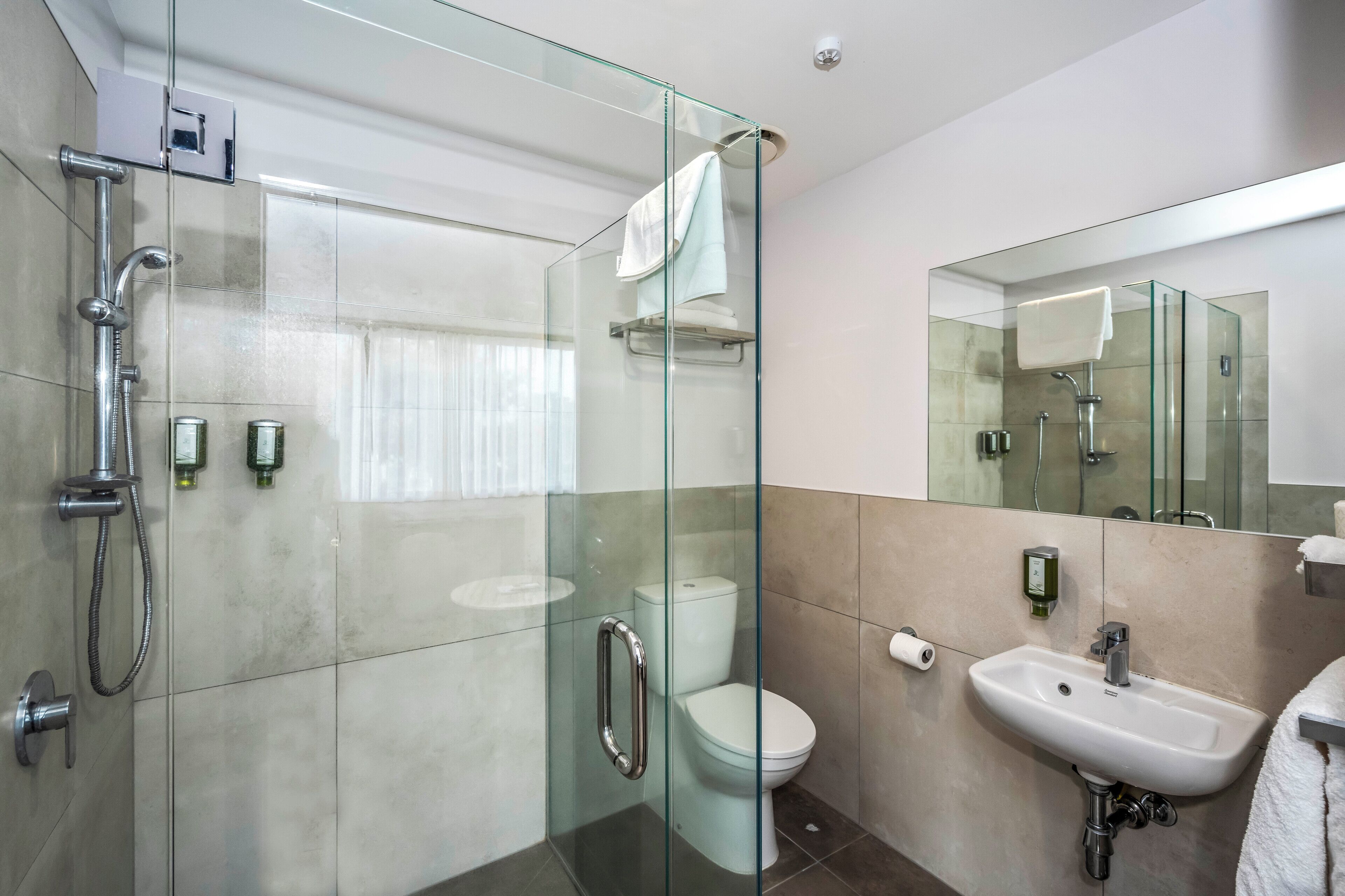 Un baño moderno con ducha envuelta en vidrio, inodoro y lavamanos.