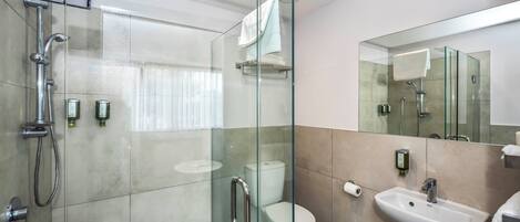 Un baño moderno con ducha envuelta en vidrio, inodoro y lavamanos.
