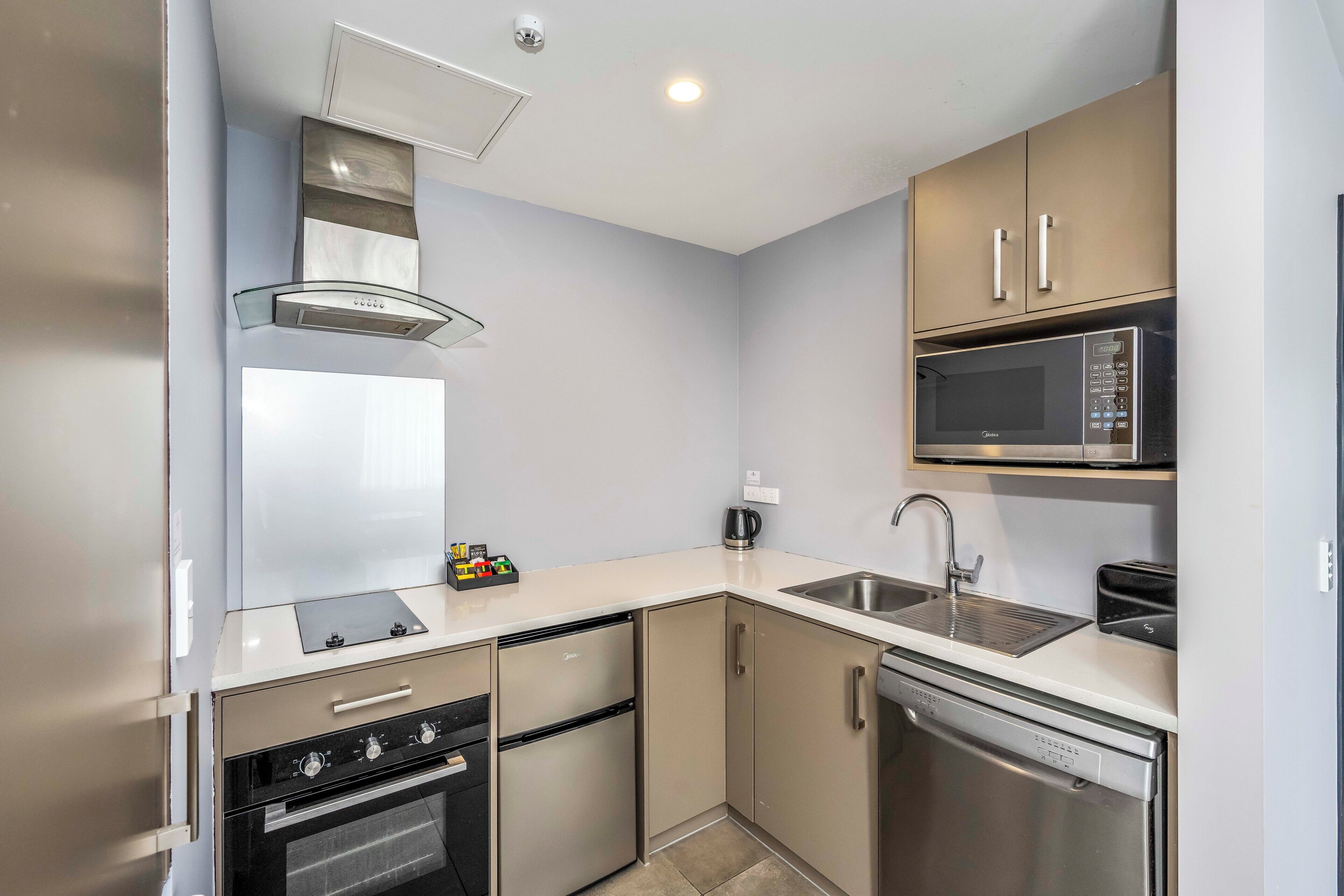 A modern kitchen with a built-in oven, dishwasher, microwave, and a coffee maker.