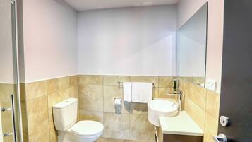 Un baño moderno con inodoro, lavamanos y ducha.