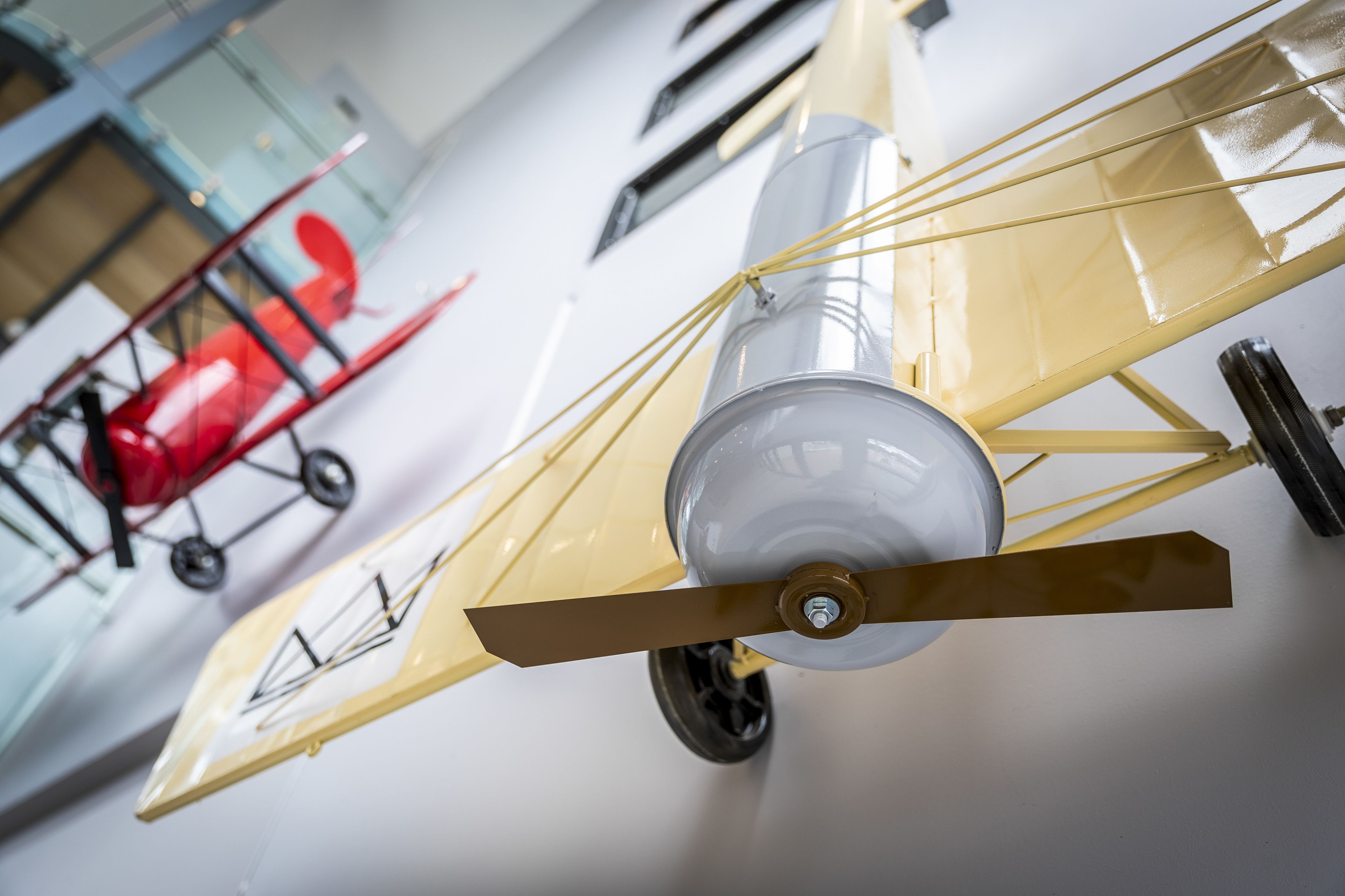 A vintage biplane with a propeller and a red biplane in the background.