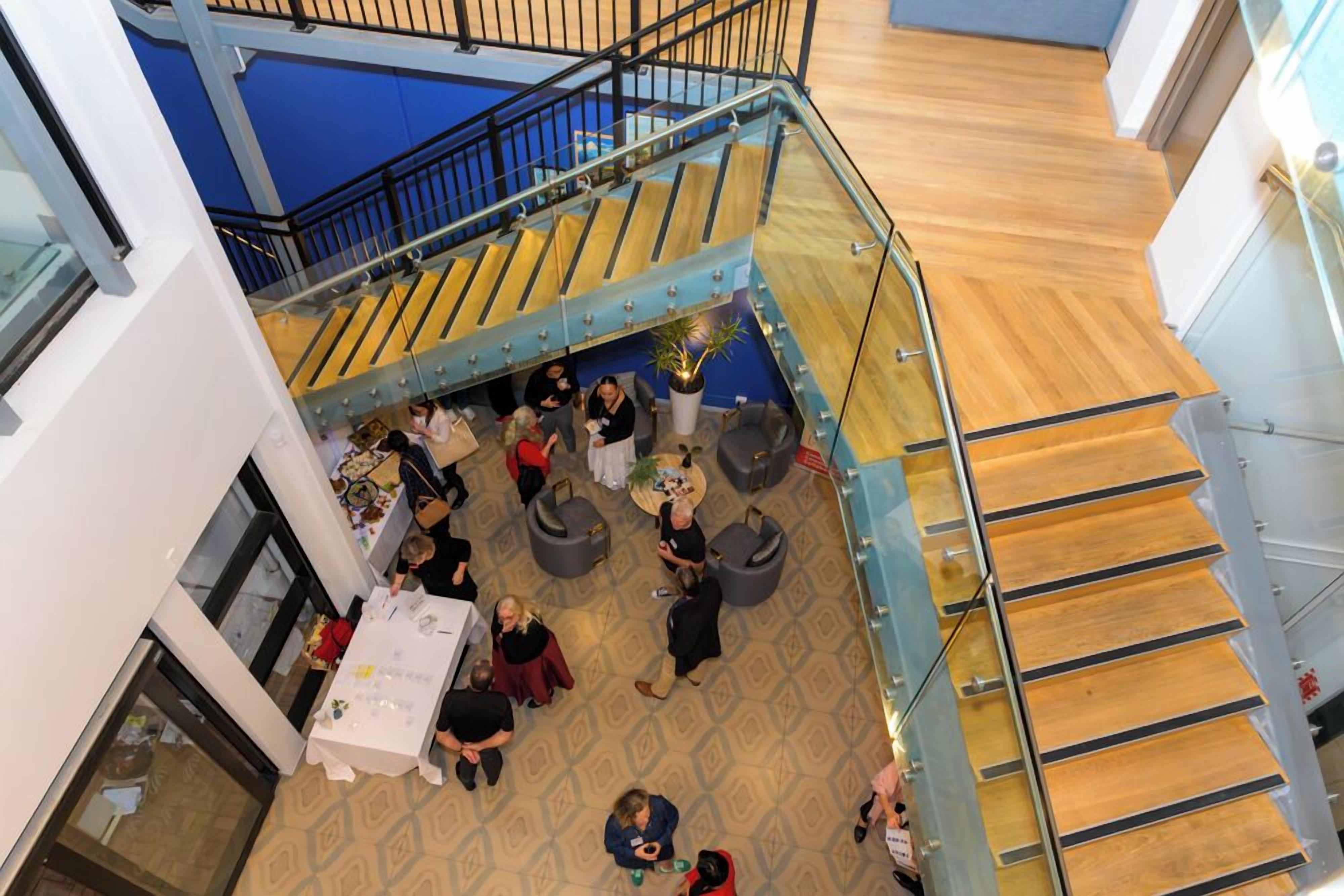 A multi-level indoor space with a staircase, seating areas, and a table with people.