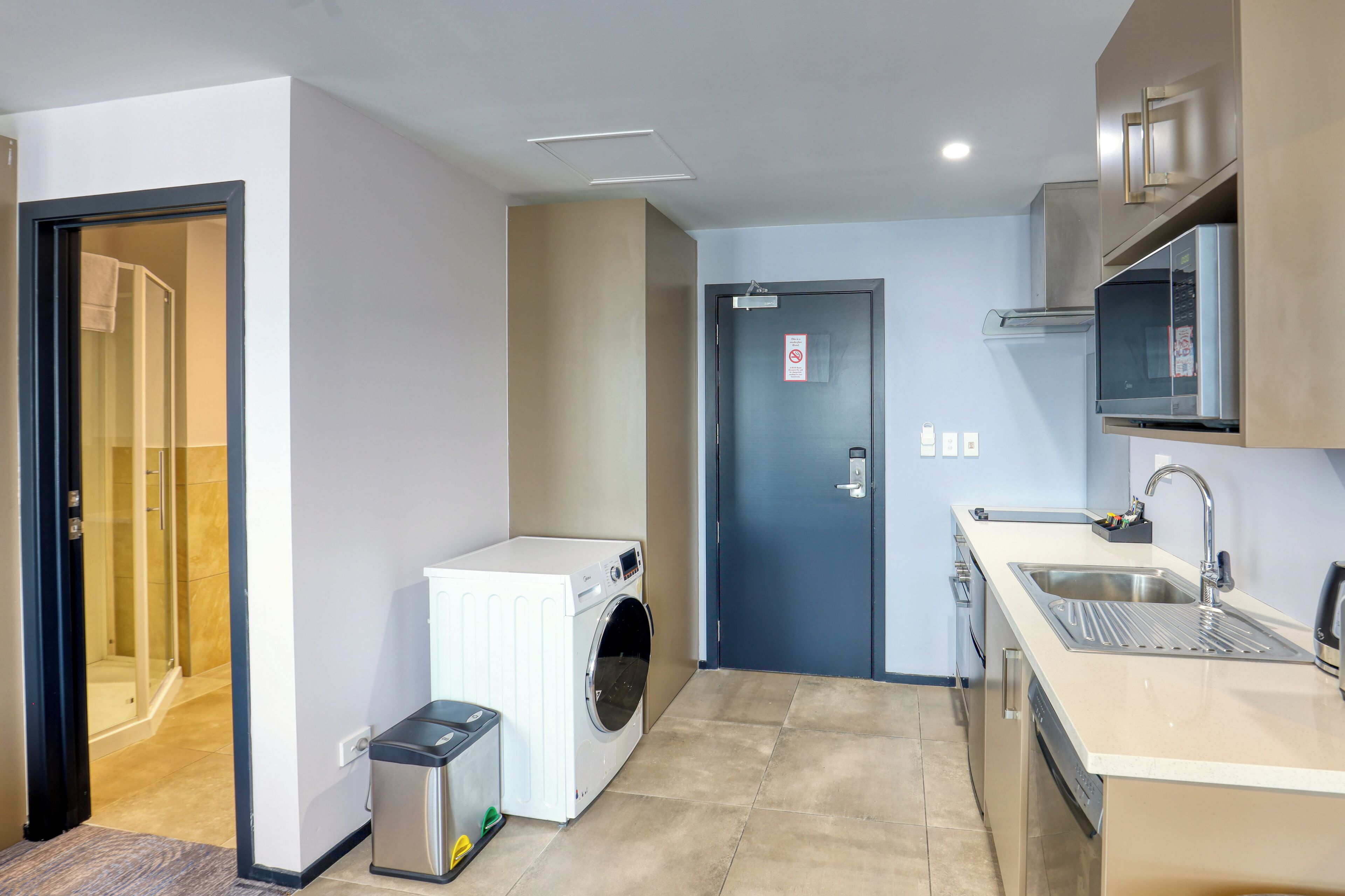 A compact kitchen with a built-in washing machine, a sink, and a microwave.
