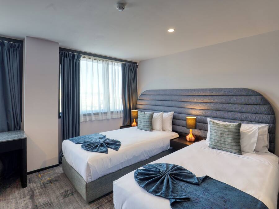 Habitación de hotel con dos camas, un escritorio y una silla.
