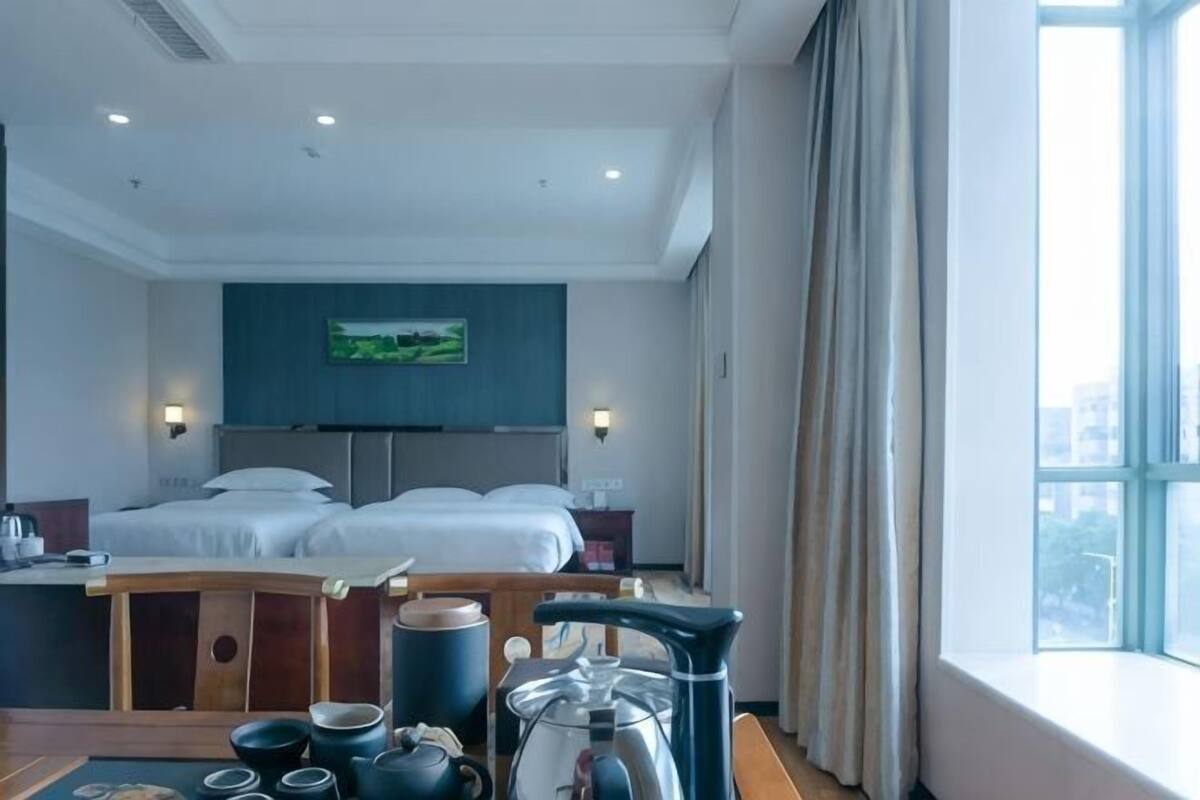 Une chambre d’hôtel avec un lit, un bureau, une bouilloire, des tasses et une théière.