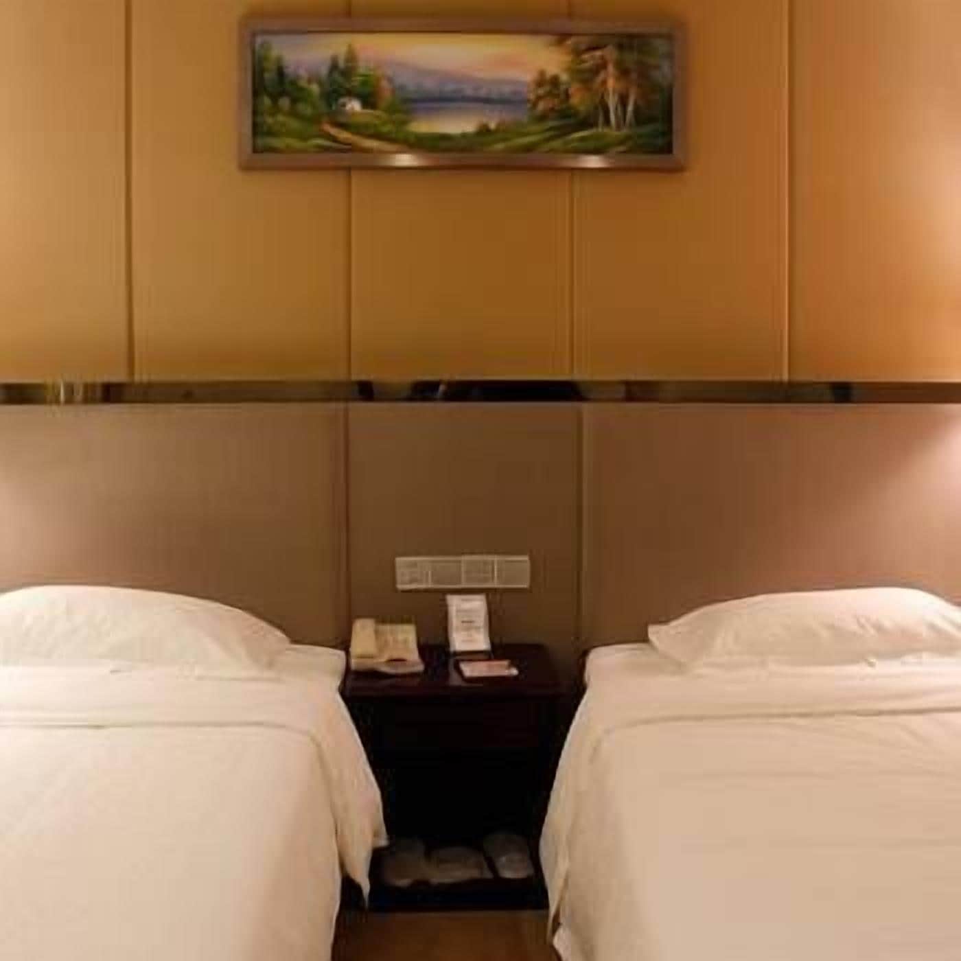 A hotel room with two beds, a nightstand, and a painting on the wall.