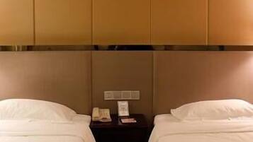 A hotel room with two beds, a nightstand, and a painting on the wall.