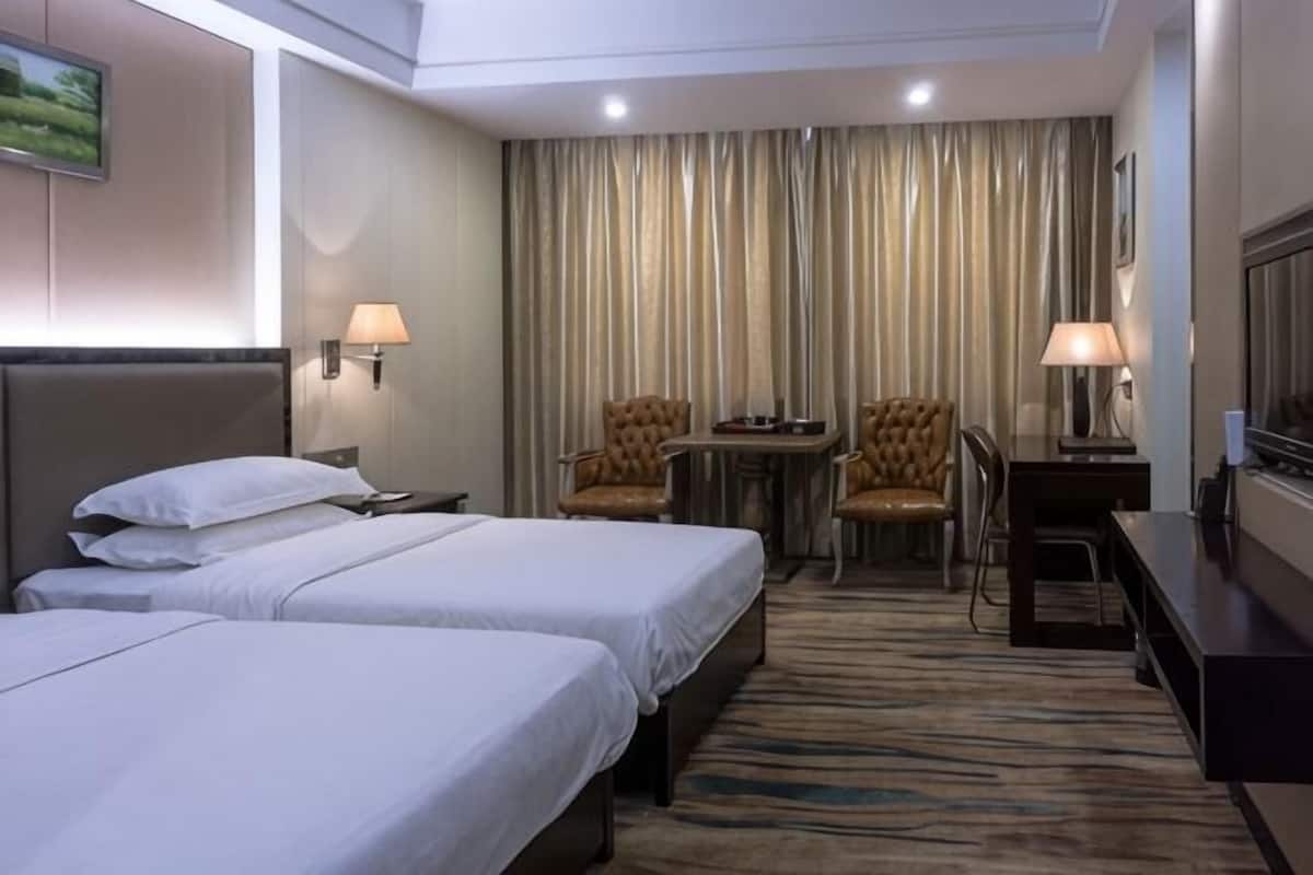 Une chambre d’hôtel avec deux lits, un bureau, deux chaises, une télévision et une vue sur les rideaux.