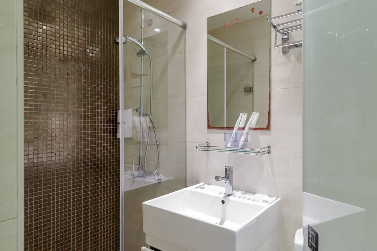 A modern bathroom with a glass shower enclosure, a white sink, and a mirror above it.