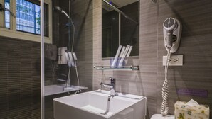 Un baño moderno con un lavamanos grande, un cabezal de ducha de mano, un secador de pelo y un espejo.