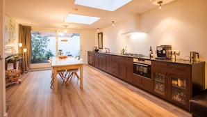 A modern kitchen with skylights, wooden flooring, and a dining area. - Puur Geluk (Groningen)
