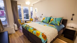A bedroom with a bed, bedside table, and a window with curtains. - Puur Geluk (Groningen)