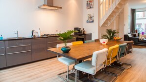 Een moderne keuken met een houten eettafel, inbouwmeubels en een trap naar een hoger niveau.