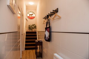 Un passadís amb una escala, un penjador i un senyal que diu 'OLIFANT JENEVRE'.