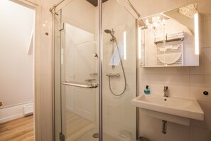 Un bany modern amb dutxa d'envidriament, un lavabo blanc i un mirall amb arranfer cortina.