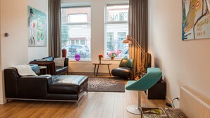 Een moderne woonkamer met een bank, fauteuil en een lamp.