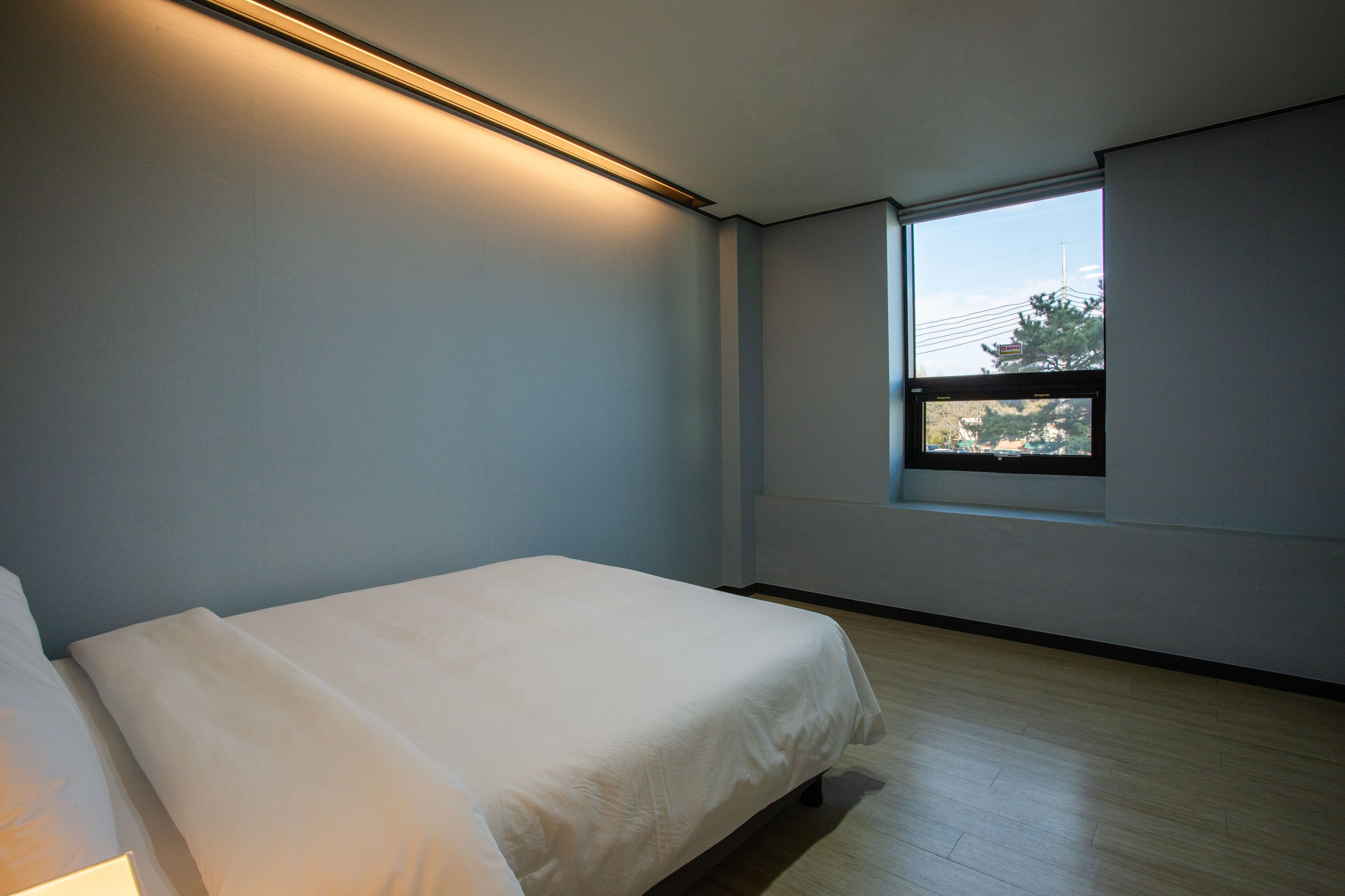 A bedroom with a single bed, a window, and a ceiling light.