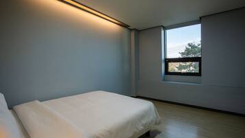A bedroom with a single bed, a window, and a ceiling light.