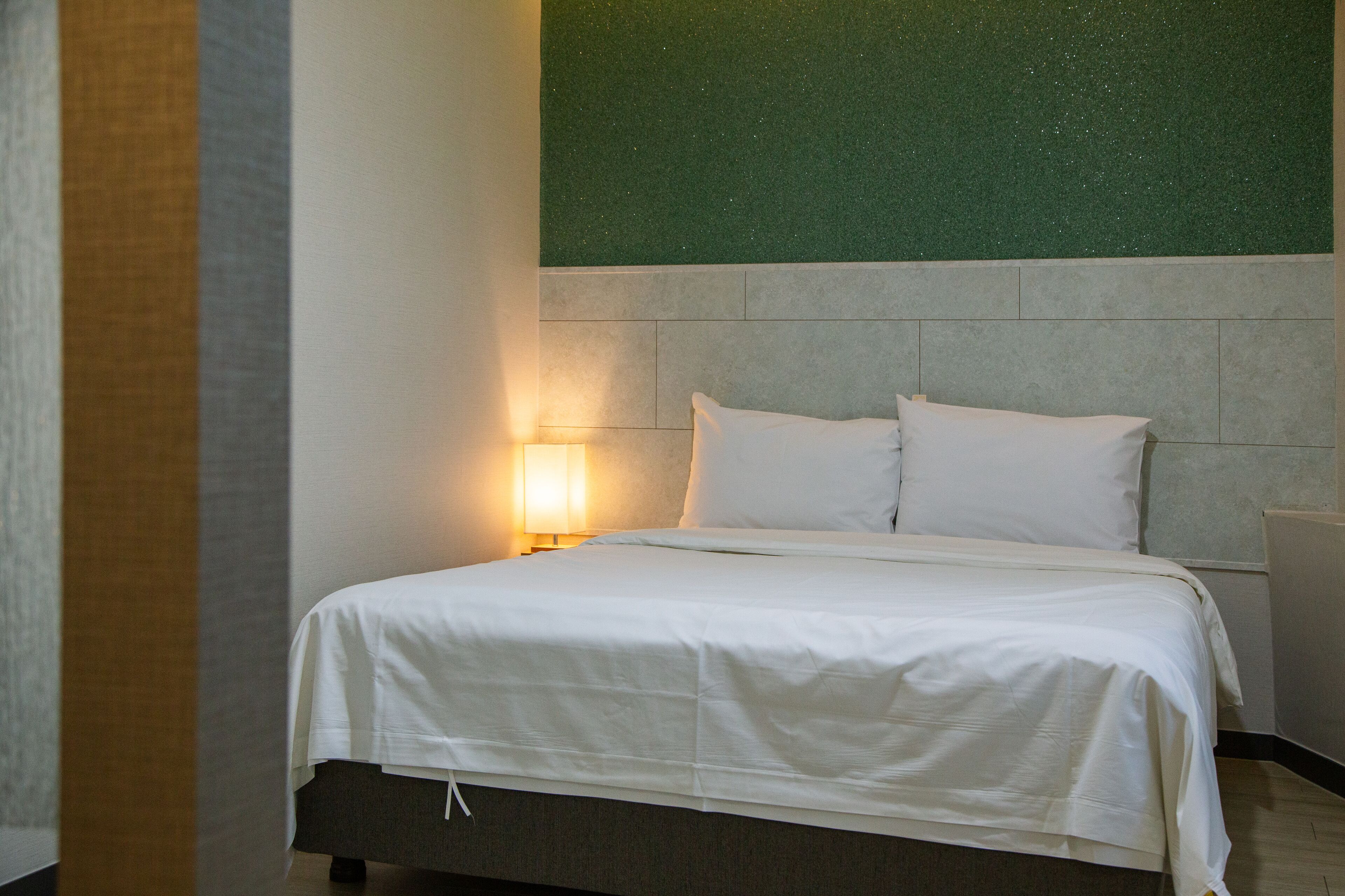 Ein Hotelzimmer mit Bett, Nachttisch und Wandlampe.