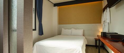 Ein Hotelzimmer mit einem Bett, einem kleinen Tisch und einem an der Wand befestigten Fernseher.