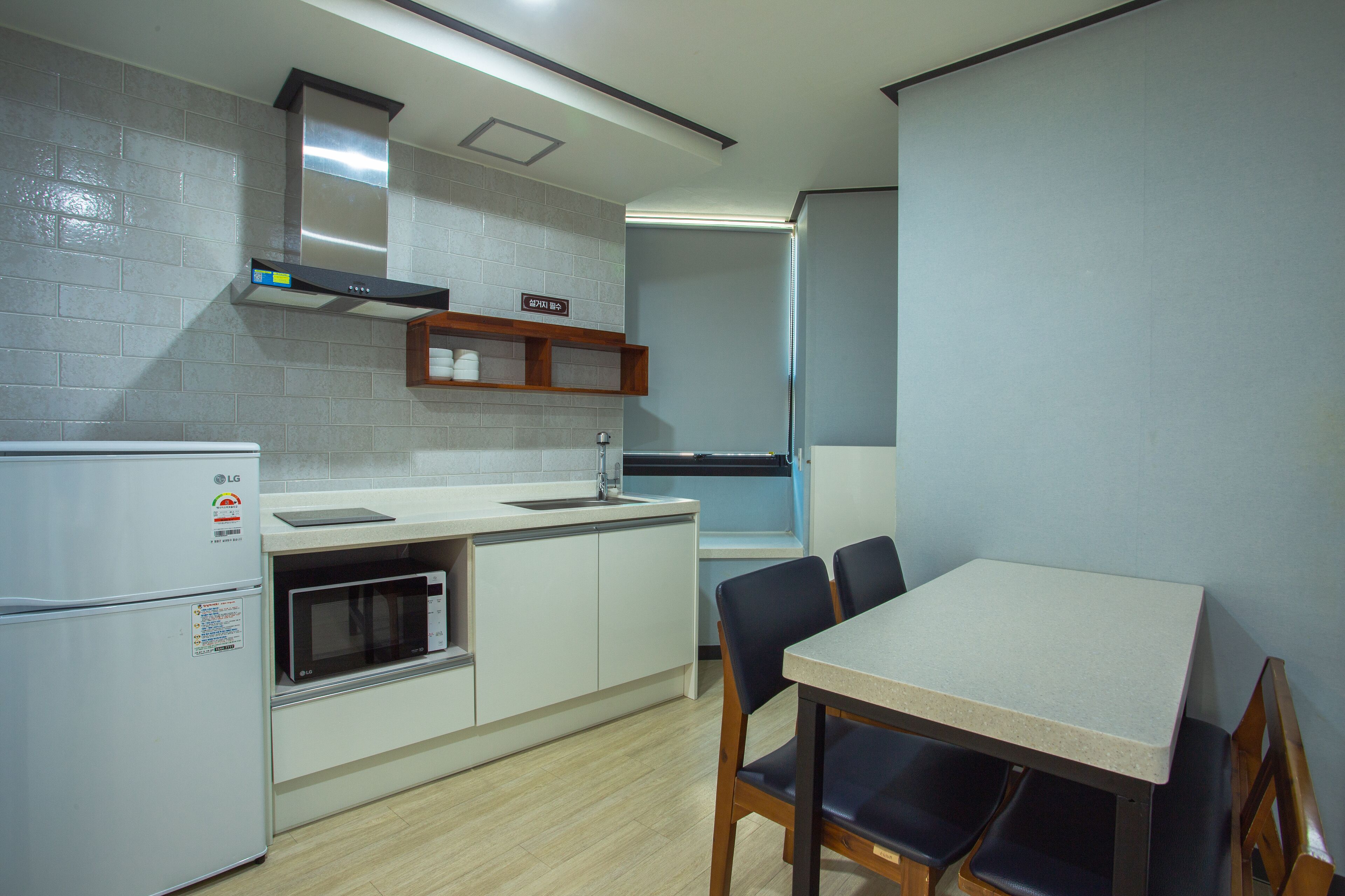 Una cocina compacta equipada con refrigerador, microondas, lavamanos y una mesa de comedor con sillas.