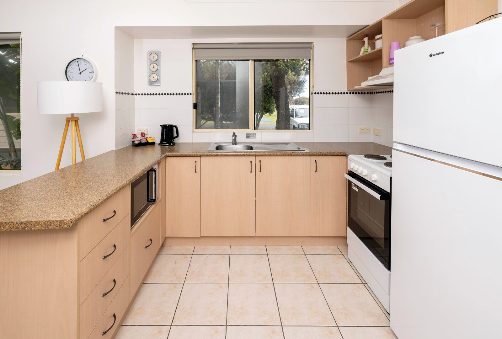 A kitchen with a window, a sink, a stove, and a refrigerator.