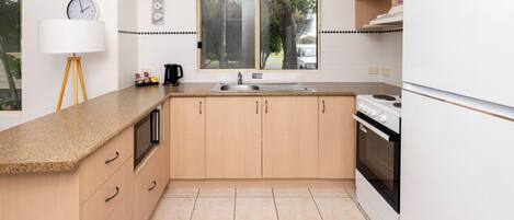 A kitchen with a window, a sink, a stove, and a refrigerator.