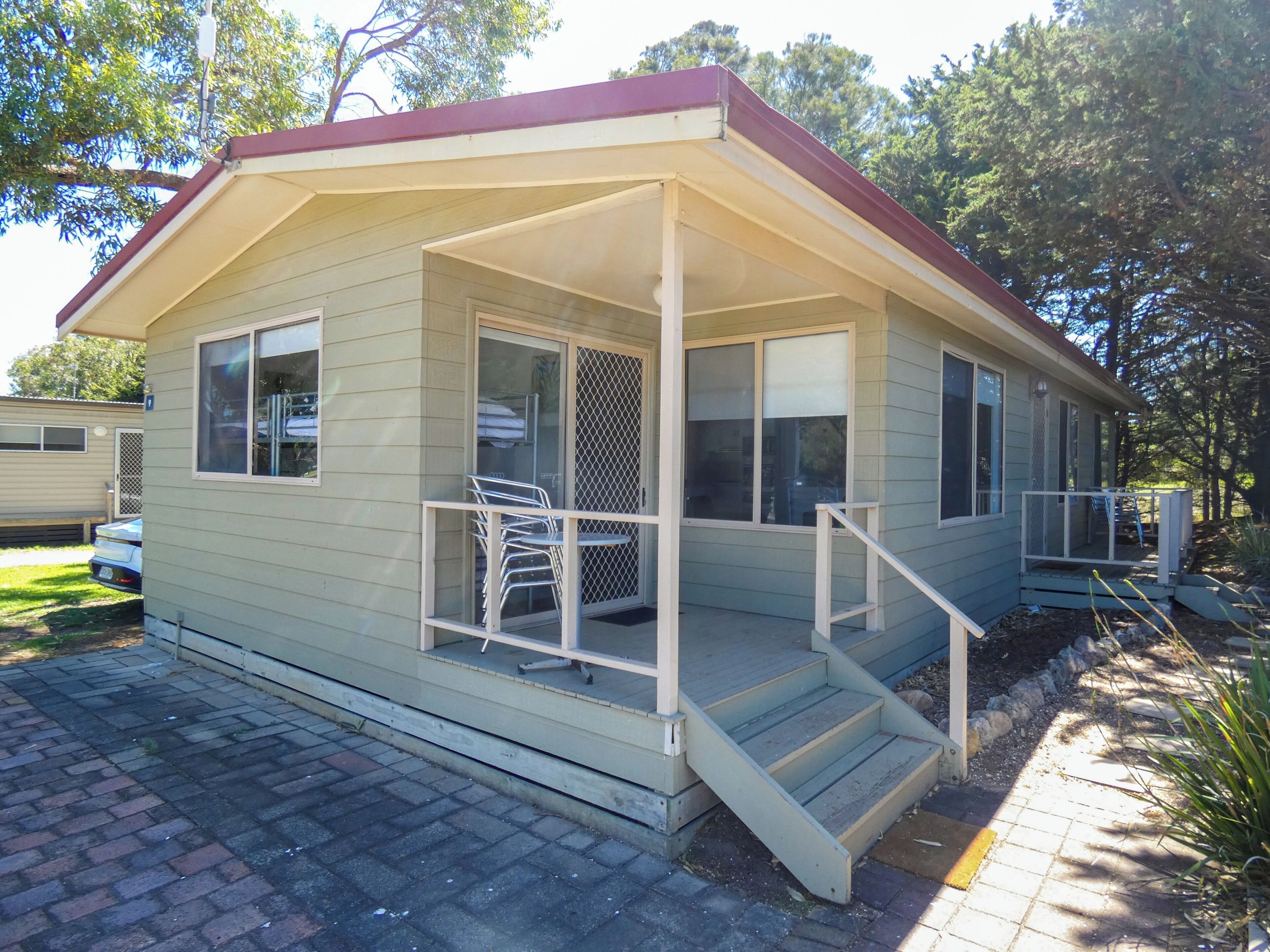 A single-story house with a porch, a small staircase, and a fenced yard.