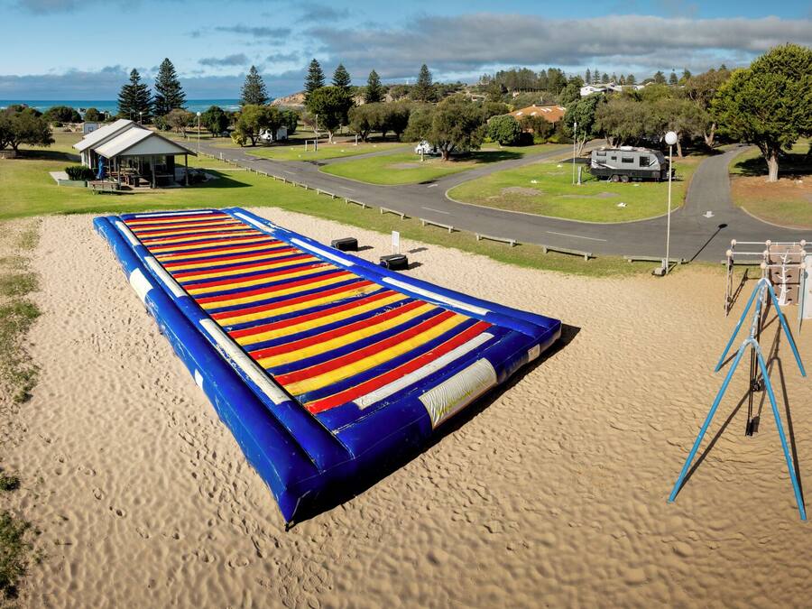 Una playa con un tobogán inflable gigante, un parque infantil y una carretera que conduce a un edificio.