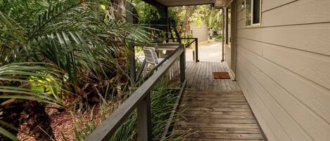 A wooden deck leading to a house with a covered porch area.