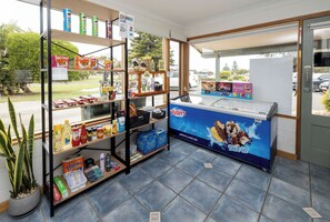A store with shelves stocked with snacks, a freezer with ice cream, and a potted plant. - BIG4 Port Elliot Holiday Park (Port Elliot)