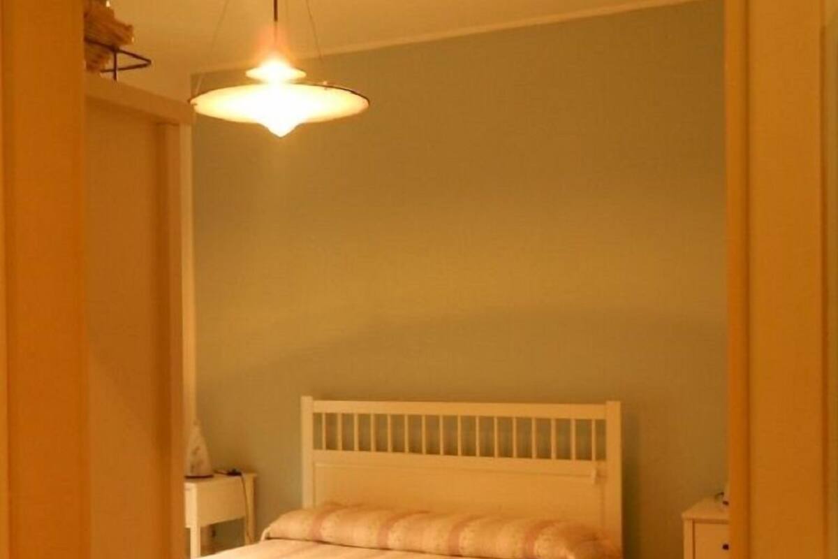 A bedroom with a bed, a nightstand, and a hanging light fixture.