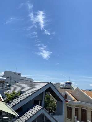 A rooftop with a sloped roof, a water tank, and a building with traditional architecture. - Win's Homestay - Hostel (Da Nang)