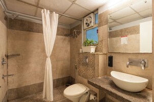 Casa de banho com chuveiro, sanita e lavatório.