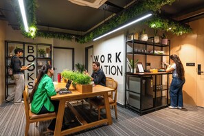 A modern workspace with a wooden table, chairs, and a bookshelf. - Moustache Jaipur (Jaipur)