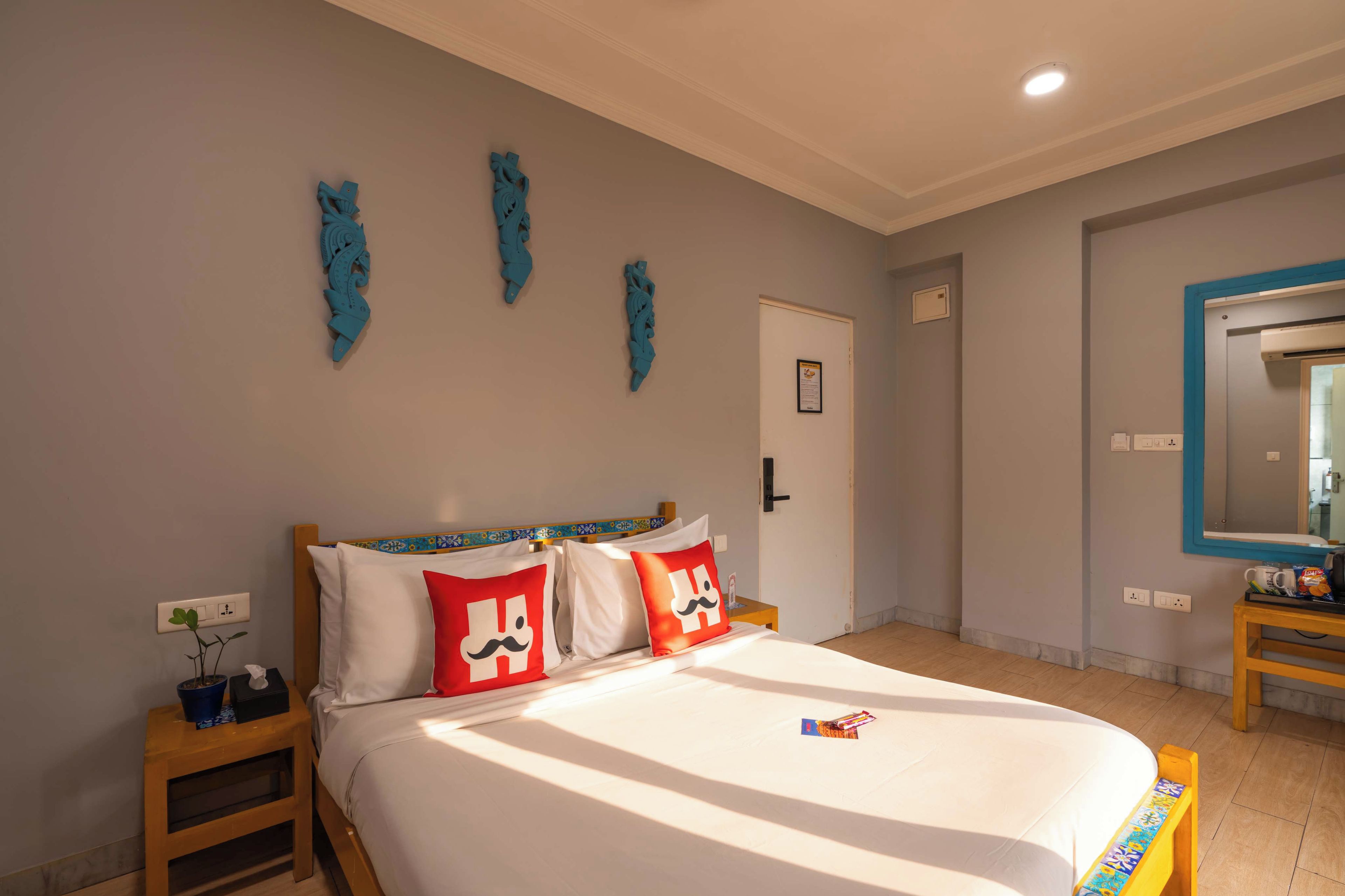 A hotel room with a bed, a nightstand, a mirror, and decorative wall art.