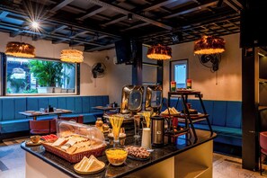 A breakfast buffet with various food items and a seating area with blue cushions. - Moustache Jaipur (Jaipur)