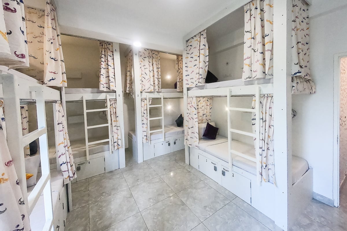 A room with bunk beds, each with a curtain featuring a mustache pattern.